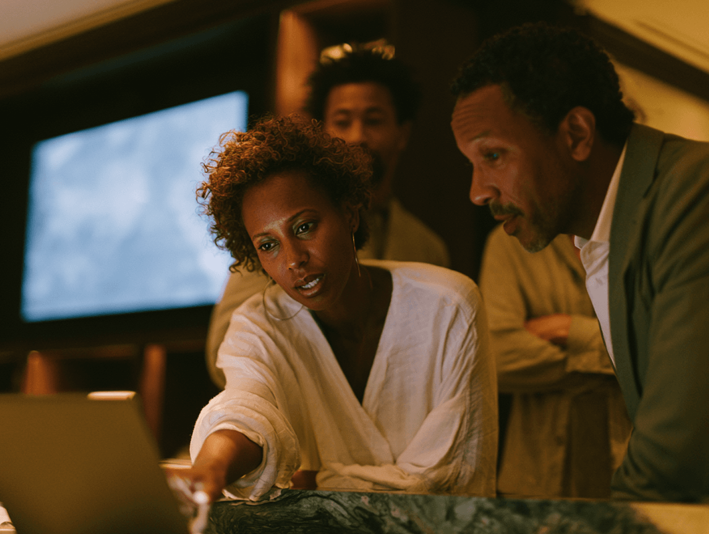 A team pointing at a laptop screen while reviewing together