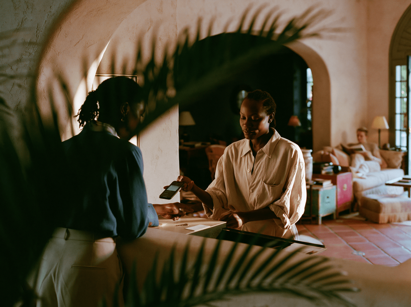 Host welcoming a guest at a plant-framed reception desk
