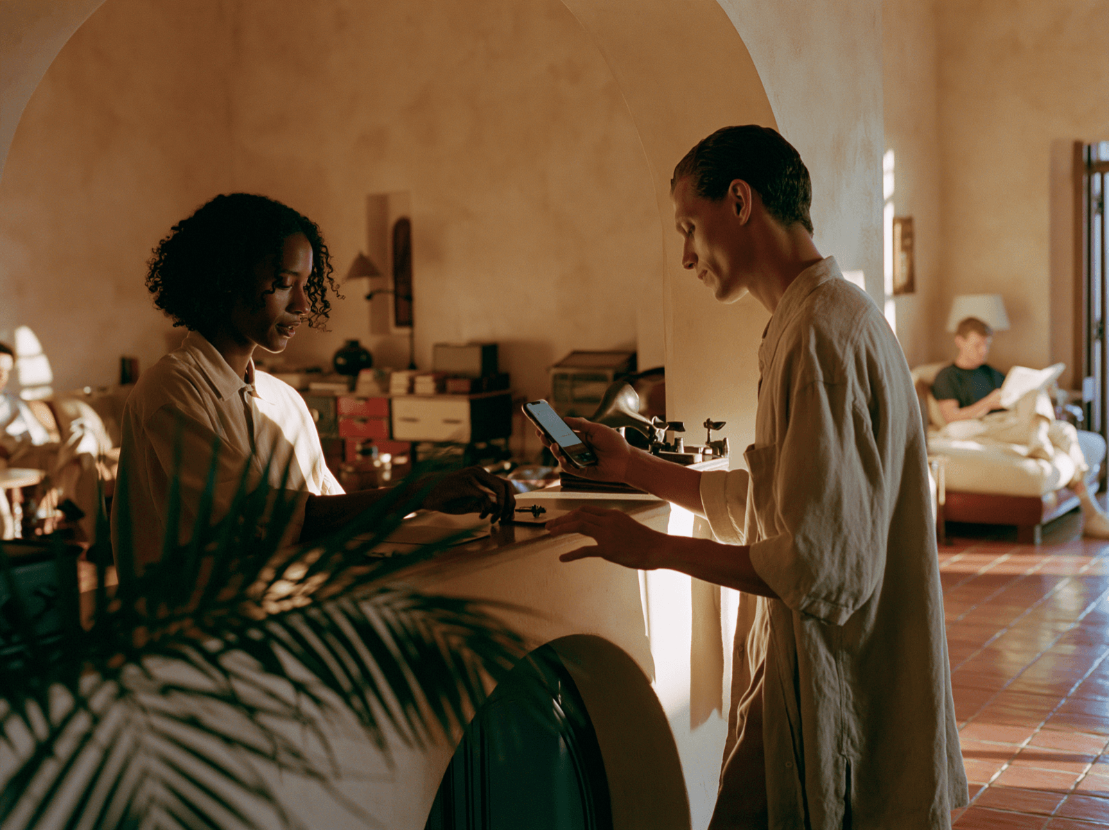 Host checking in a guest at a sunlit reception counter