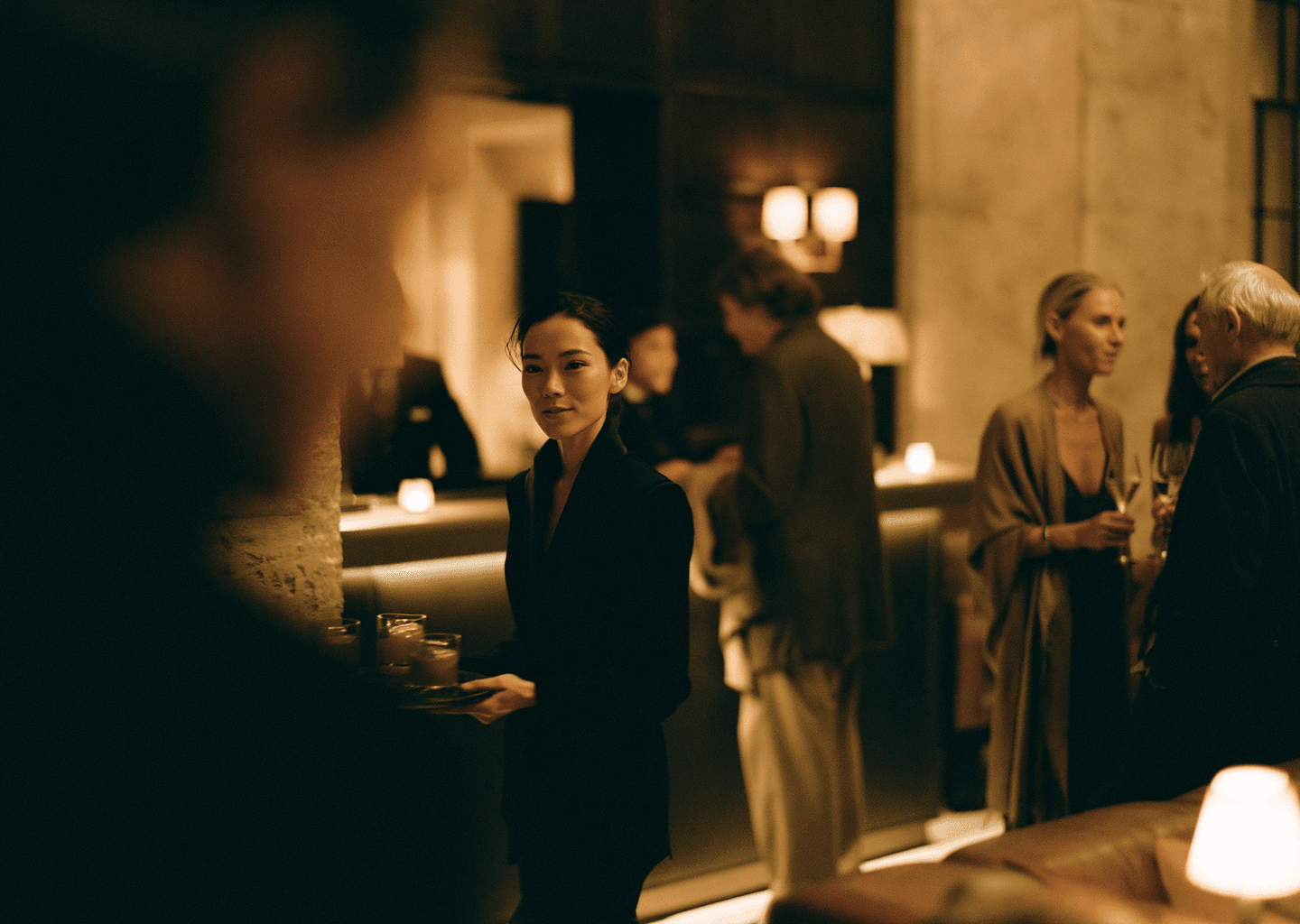 Staff member carrying candles through a dim member lounge in the evening