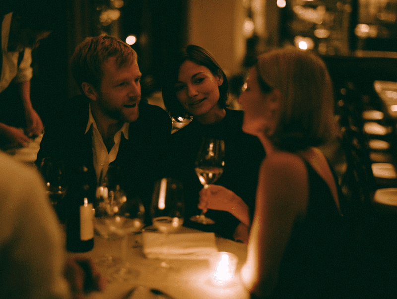 Friends toasting wine at a candlelit dinner table