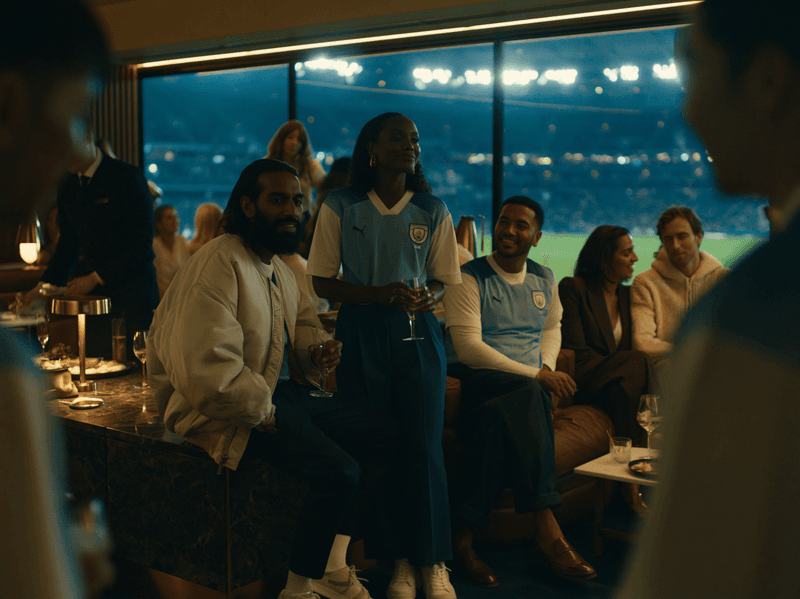 Guests socialising in a stadium suite above the floodlit field