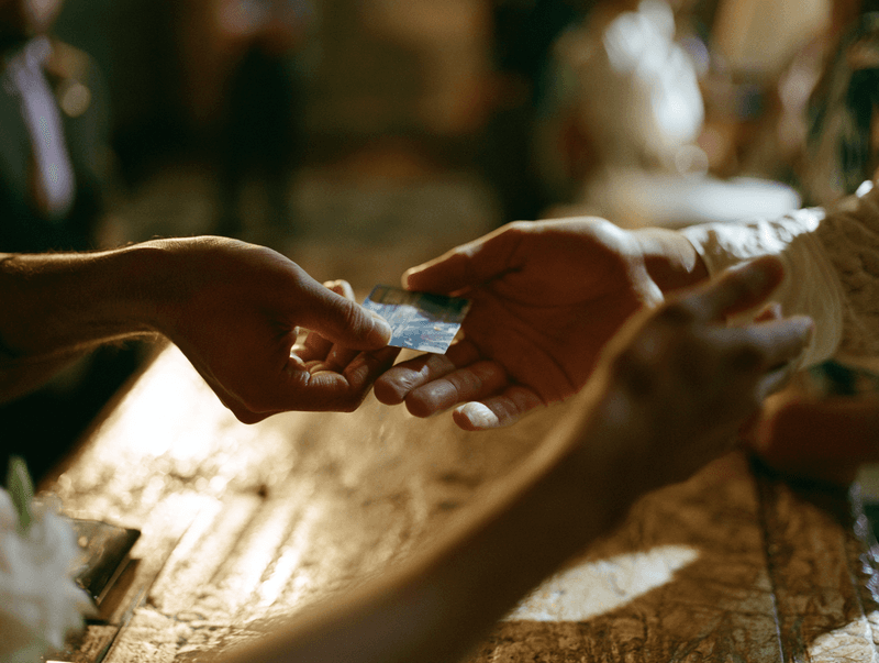 Member handing a card across a candlelit desk